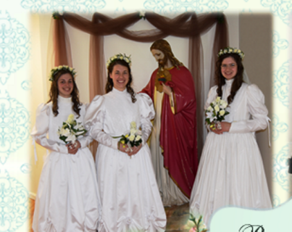 Three young women, who are ready to make vows as religious sisters, stand in wedding gowns next to a statue of the Sacred Heart of Jesus.